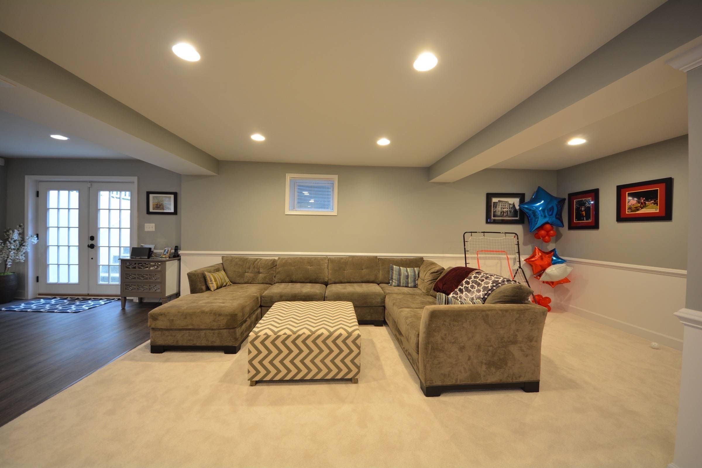 Basic family room layout with comfortable couch and natural light pouring in from double-door entrance. A comfortable approach is both affordable and still aesthetically pleasing.